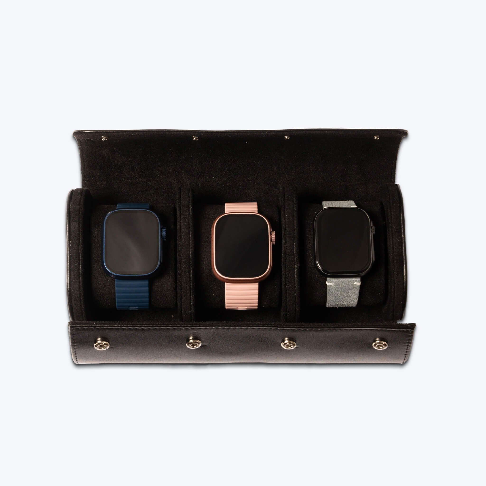 Black leather watch roll with three smartwatches inside of it.