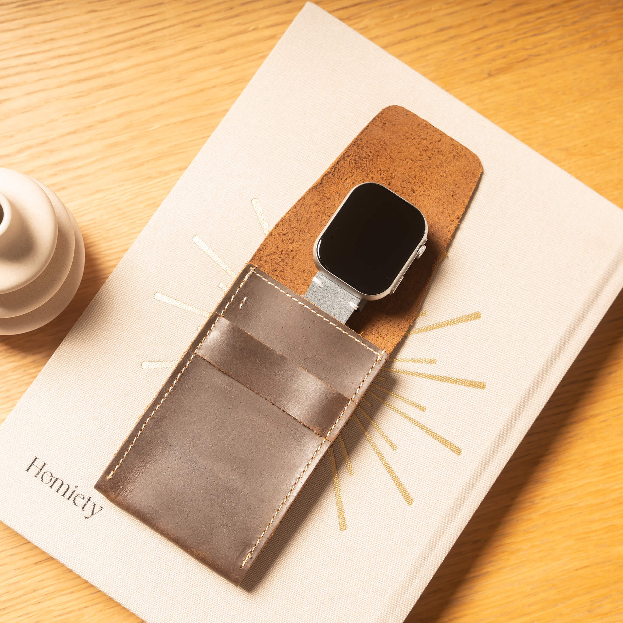 leather watch pouch on a book in a lifestyle setting background.