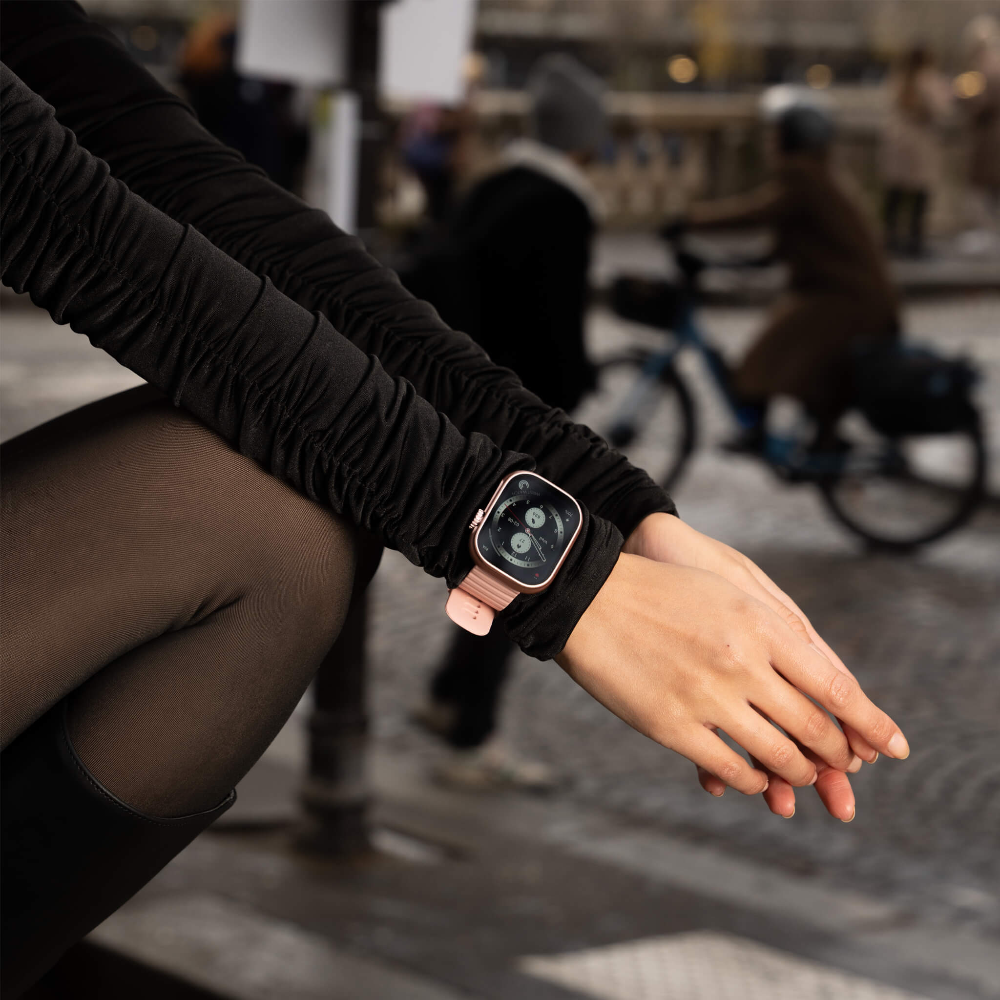 Model sitting down wearing pink lynx smartwatch.